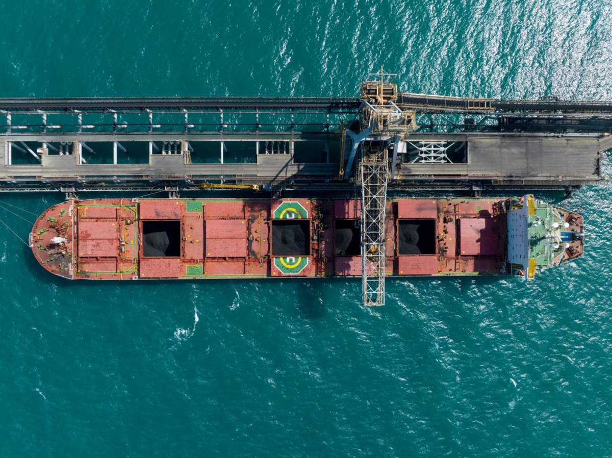 Overhead view of a bulk carrier being loaded with coal at a ship loader